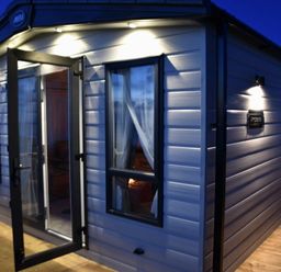 an exterior view of a holiday cabin with lights at Perran Sands - Holiday Accommodation 7528, Perranporth, Cornwall, United Kingdom
