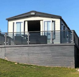 a holiday home with a balcony and large windows at Perran Sands - Holiday Accommodation 7528 Perranporth, Cornwall, United Kingdom