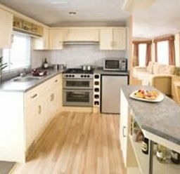 a kitchen with cabinets, appliances, and a dining area at Perran Sands - Holiday Accommodation 8131 in Perranporth