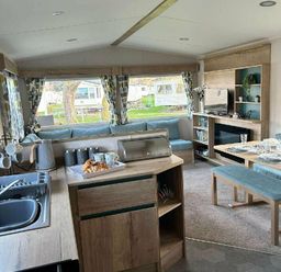 a living room and kitchen area with a sofa, dining table, and kitchen appliances at Butlins Minehead - Holiday Accommodation 826 in Minehead