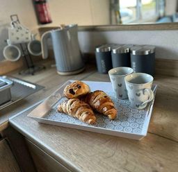 a tray with croissants and two cups on a kitchen counter at Butlins Minehead - Holiday Accommodation 826 in Minehead