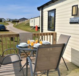 a dining table with drinks on a wooden deck at Perran Sands - Holiday Accommodation 8302 in Perranporth