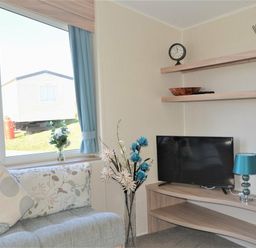 a living room with a TV on a shelf and a window at Perran Sands - Holiday Accommodation 8302 in Perranporth