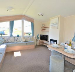 a living room with a sofa, dining table, and television at Perran Sands - Holiday Accommodation 8302, Perranporth