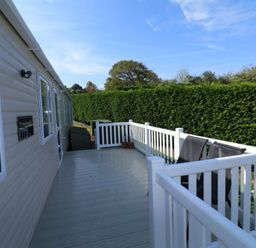 a deck area with a railing and chairs at White Acres Holiday Park - Holiday Accommodation 895 in Newquay