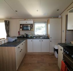 a kitchen area with a stove, refrigerator, and seating in White Acres Holiday Park - Holiday Accommodation 895, Newquay