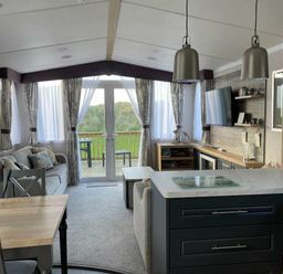 a living room with a dining table and kitchen area at Perran Sands - Holiday Accommodation 8982, Perranporth