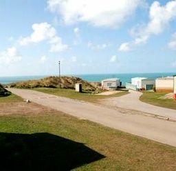a view of camping trailers and a road with ocean in the background at Perran Sands - Holiday Accommodation 9159 in Perranporth