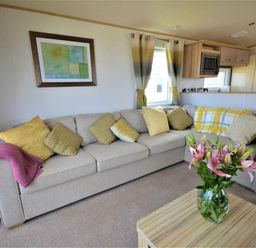 a living room with a sofa and flowers on a table at Perran Sands - Holiday Accommodation 9657 in Perranporth