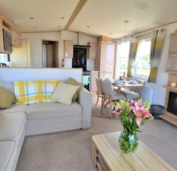 a living room with a sofa, coffee table, and dining area at Perran Sands - Holiday Accommodation 9657 in Perranporth