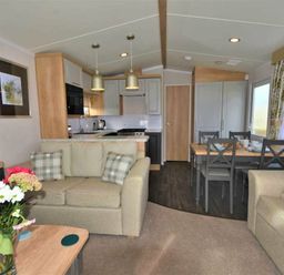 a living room with a sofa, dining area, and kitchen at Perran Sands - Holiday Accommodation 9871 in Perranporth
