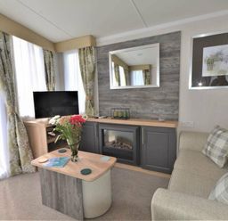 a living room with a television, a mirror, and a sofa at Perran Sands - Holiday Accommodation 9871 in Perranporth