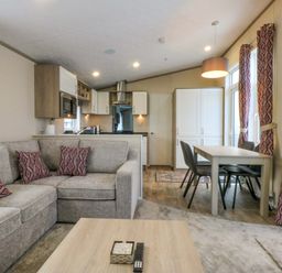 A living room with a sofa and dining area at Blue Skies in Caernarfon