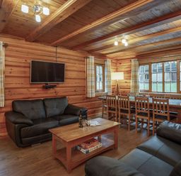 A living room with a sofa and dining area at Kinder Lodge (Pet) Fowlis near Dundee