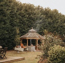 A gazebo in a garden with seating and trees at Garden Pod in Waltham