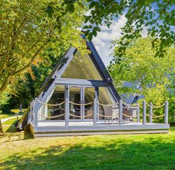 A house with a deck and chairs surrounded by trees at St Ives Studio in Praze-An-Beeble