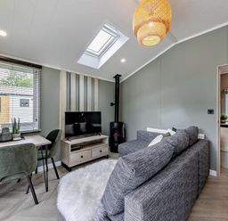 A living room with a sofa dining table and television at Prion Spa in Llandyrnog
