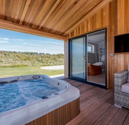 An outdoor area with a hot tub and glass door at Darwin Retreat in Wigton