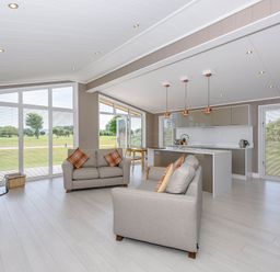 A living room with a sofa and kitchen area at Darwin Retreat in Wigton