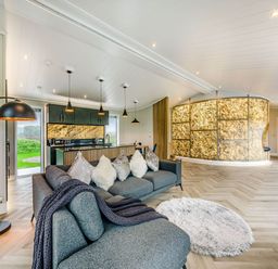 A living room with a sofa and kitchen area at The Sheraton Retreat in Wigton