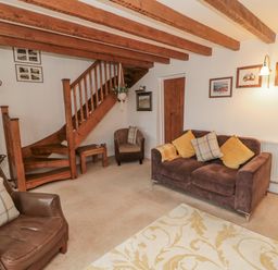 A living room with seating and staircase at 21 High Street in Scarborough