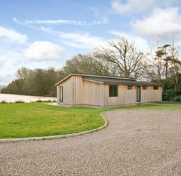 A wooden house with a gravel driveway and grassy area at Lawson in Wigton