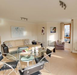 A living room with a sofa, dining table and television at Harbourside Apartment in Weymouth