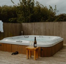 A hot tub with champagne and glasses on a wooden deck at Wellington in Wigton
