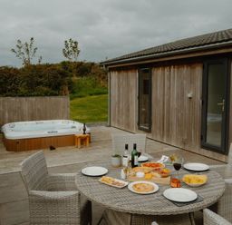 An outdoor patio with a hot tub and table set with food and drinks at Wellington in Wigton