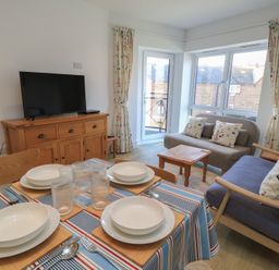 A living room with a television and dining table at Brewery View in Weymouth