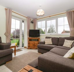 A living room with sofas and a television at Dovecote Cottage in Corse near Gloucester