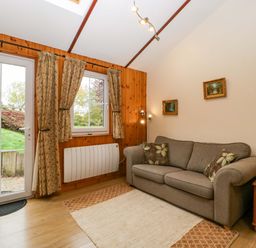 A living room with a sofa and window at The Log Cabin in Corse near Gloucester