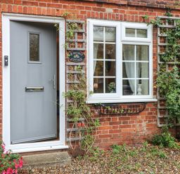 An outdoor entrance with a grey door and window at Beeble Cottage in Fakenham