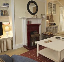 A living room with a fireplace and a television at St Leonards in Salcombe