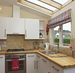 A kitchen with white cabinets and wooden countertops at St Leonards Salcombe