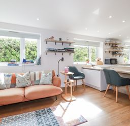 A living room with a sofa and a kitchen area at Hillbre in Trevone