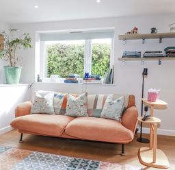 A living room with a sofa, bookshelf, and plant at Hillbre in Trevone