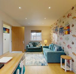 A living room with a sofa and dining table at Summerleaze Cottage 2 Spa Bude