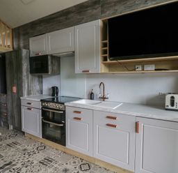 A kitchen with cabinets, sink, and appliances at The Family Pod in Swansea