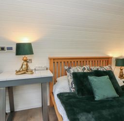 A bedroom with a bed and green accents at Garden Lodge 1 in Swansea