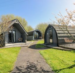 Three glamping pods with a pathway and grass at Glamping Pod 1 Oldwalls, Llanrhidian, Gower