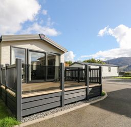 A mobile home with a deck and glass railing at Altair Lodge in 
