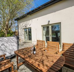 An outdoor area with a wooden table and chairs at Oak Tree Cottage in Oldwalls, Llanrhidian, Gower