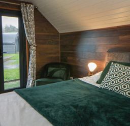 A bedroom with a bed and a chair at Garden lodge 3 Swansea
