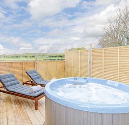 An outdoor area with a hot tub and loungers at Typhoon Lodge in Winchester