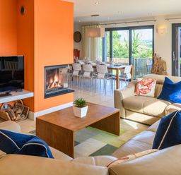 A living room with a fireplace and dining area at Nan's House Spa Marhamchurch
