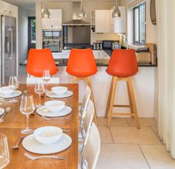 A kitchen with bar stools and a dining table at Nan's House Spa in Marhamchurch
