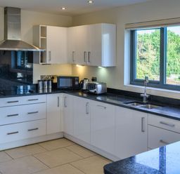 A kitchen with appliances and a window at Nan's House Spa in Marhamchurch