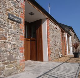 An exterior view of Barleypark with stone walls and a door in Marhamchurch