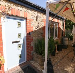 An entrance with a front door and outdoor seating area at The Old Barn in Stourton Caundle near Stalbridge